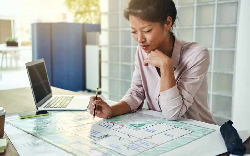 Woman working at a desk with a laptop in an office setting.